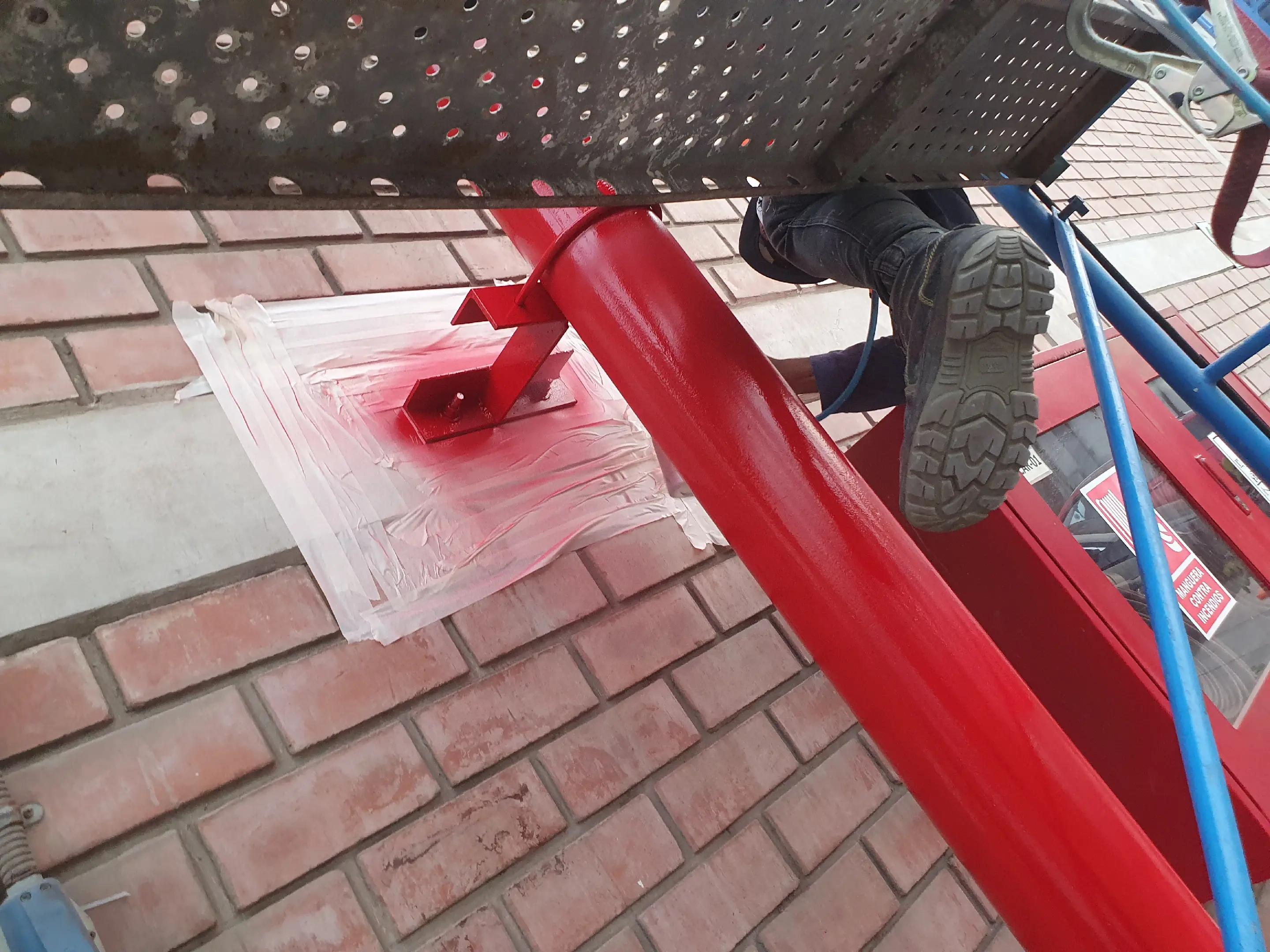 Tuberías del sistema contra incendios recién pintadas de rojo en un edificio comercial, trabajo de mantenimiento de ADN Construcción